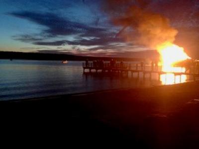 large fire burning at night on shore of Cayuga Lake